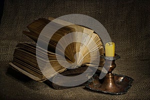 Old books with yellow candle on canvas background